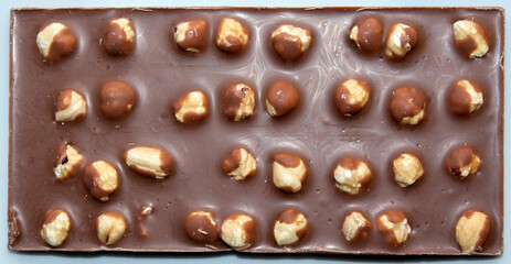 close-up of milk chocolate bar with whole hazelnuts. selective focus. top view