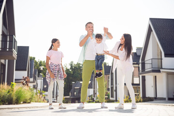 Full size photo of happy positive cheerful smiling family go walk together dad and mom carry little son outside outdoors