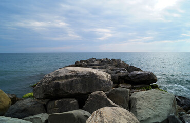 Large mountain rocks are littered with a path into the sea. Beautiful seascape. The horizon line between the evening sky and the sea.