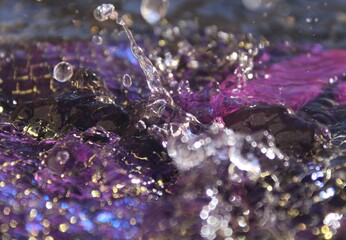 Wallpapers. Frozen movement of water. Drops of water falling and splashing. Sparkles, reflections of light. Vibrant purple color. 