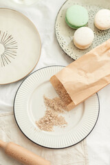 Hazelnut flour. Walnut flour in a paper bag on a light plate with French pastries macaroons in pastel light colors. Ingredients for a pastry shop and bakery
