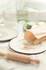 Hazelnut flour. Walnut flour in a paper bag on a light plate with French pastries macaroons in pastel light colors. Ingredients for a pastry shop and bakery