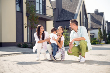 Portrait of attractive cheerful careful family having fun mom dad playing with kids spending free...
