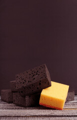 kitchen sponges for washing dishes on a black background with copy space. a bunch of black washcloths, among them one yellow.