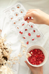 Making homemade chocolate, confectioner puts ingredients into plastic transparent molds