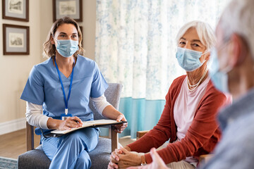 Nurse listening to senior couple during a home visit