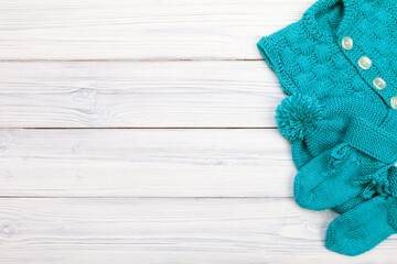 blue knitted clothes for baby on white wooden background