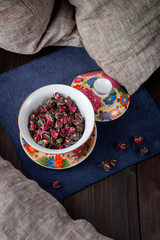 Beautiful cup with dried tea rose flowers