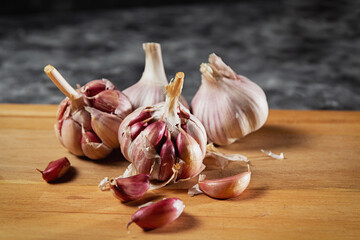 Garlic clove of the purple type, widely used as a seasoning. Wooden base and dark background. Side space for texts.