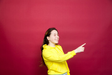 Portrait of   beautiful young girl in   yellow hoodie  against  red