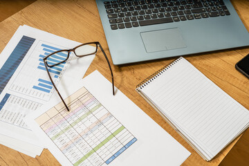 Work table at home with pen, papers, bills, charts, glasses, computer and calculator. Concept work at home, checking accounts, economy of the home. Aerial view.