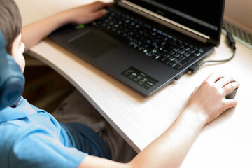 Smiling boy using laptop at home. On-line or e-learning education on quarantine. Soft focus