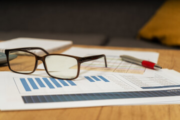 Work table at home with pen, papers, bills, charts, glasses, computer and calculator. Concept work at home, checking accounts, economy of the home. View to normal.