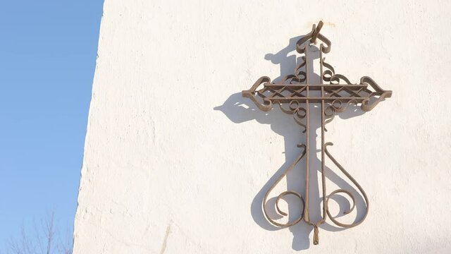 The metal cross sign on the wall of the church on a sunny day