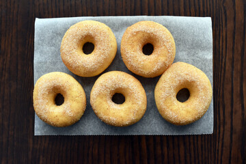 Cinnamon sugar donuts on parchment paper on wood table. Flat lay top view photo. Food from above. 