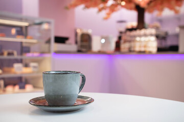A cup of coffee against the blurry background of a restaurant bokeh.