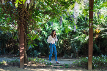 Chica joven guapa en un parque usando el smartphone y dando un paseo en primavera