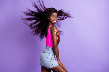 Photo portrait of african american woman with flying hair loking behind shoulder isolated on pastel pink colored background