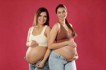 Happy young pregnant women on red background