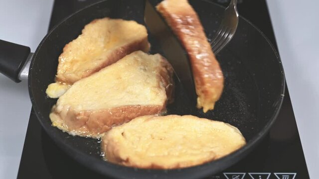 Woman flips in a frying pan ruddy crust up fried Spanish torrijas or French toasts. Popular dessert for Christmas, Easter or Pascua. 4k resolution