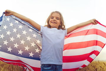 Adorable patriotic girl wearing an American flag in a beautiful wheat field