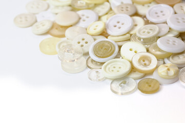 White and beige buttons on a white background. Old vintage buttons close up. Copy space. Side view. The background is made of buttons in natural shades.