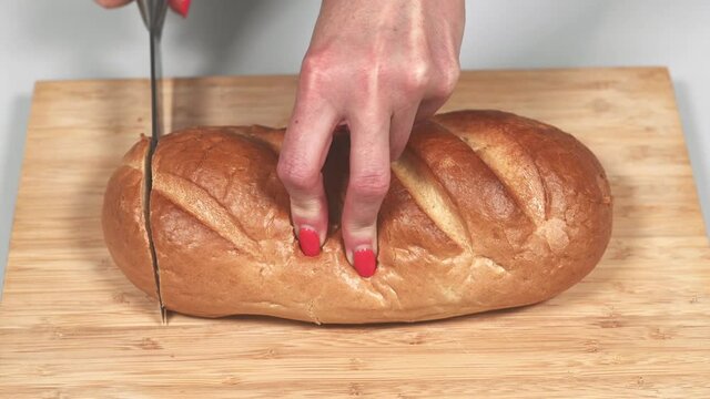 Woman cuts bread on kitchen board with a knife for Spanish torrijas or French toasts. Popular dessert for Christmas, Easter or Pascua. 4k resolution