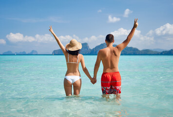 Rear view of happy couple with hads up enjoying warm tropical ocean water.