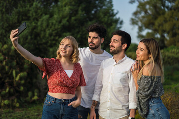 Grupo de amigos disfrutando de zona verde en primavera tomando selfies