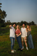Fototapeta premium Grupo de amigos disfrutando de zona verde en primavera tomando selfies