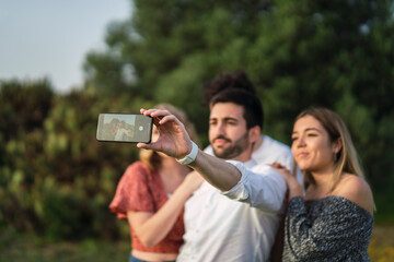 Grupo de amigos disfrutando de zona verde en primavera tomando selfies
