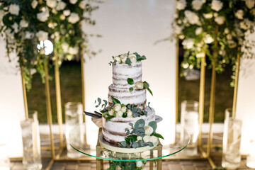 Beautiful delicious white wedding cake at the evening. Wedding cake for guests and brides