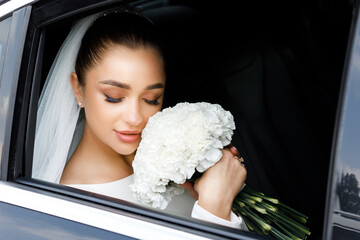 Portrait of a beautiful young bride in the car. Close-up portrait of a pretty bride in a car window