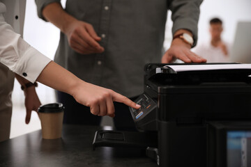 Employees using modern printer in office, closeup