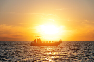 Obraz premium Unidentified tourist boat without people in the sea at sunset