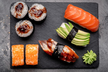 Sushi set of Rolls and nigiri with avocado, salmon and eel on a stone board. Japanese food.