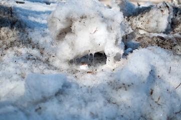 Large lumps of old dirty snow with icicles from the spring sun.