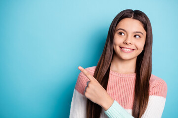 Photo of young school girl happy smile indicate finger empty space advert promo advise choose isolated over blue color background