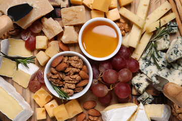 Cheese plate with honey, grapes and nuts on wooden board, top view