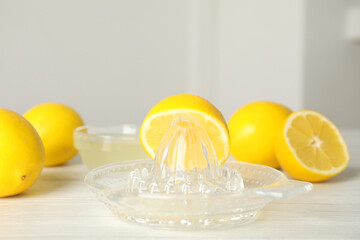 Plastic juicer with half of lemon on white wooden table