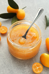 Delicious kumquat jam and fresh fruits on light grey table