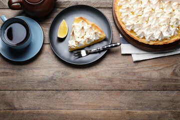 Cut delicious lemon meringue pie served on wooden table, flat lay. Space for text