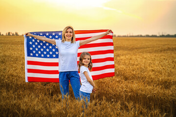 Mother and daughter with American Flag in a beautiful wheat field