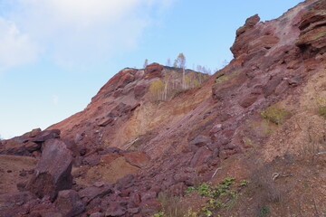 Red hills with birches against a blue sky.