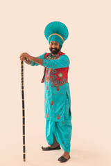 A man in Bhangra costume holding the Khunda	