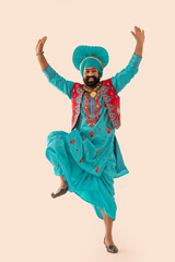 A Bhangra dancer demonstrating a dance step with hands in the air.	