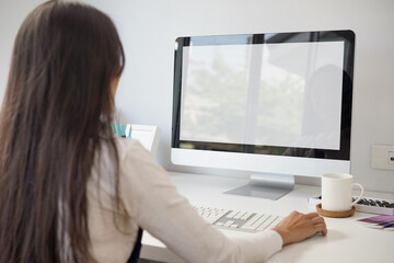 Fototapeta na wymiar Mockup blank white desktop screen computer with a woman working in background. White screen computer for graphic montage. clipping path