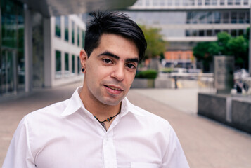 Fototapeta premium Portrait of a young Hispanic or Latino man at the entrance of a building. Modern Urban Concept.