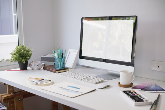 Working space of artist with computer, canvas, coffee cup, book and office supplies in home office room. clipping path
