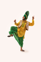 A Bhangra dancer presenting a step with hand gestures and a leg lifted up.	